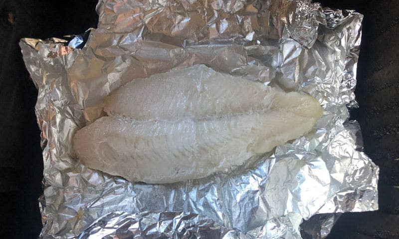 Single Basa fillet inside open foil parcel positioned in air fryer