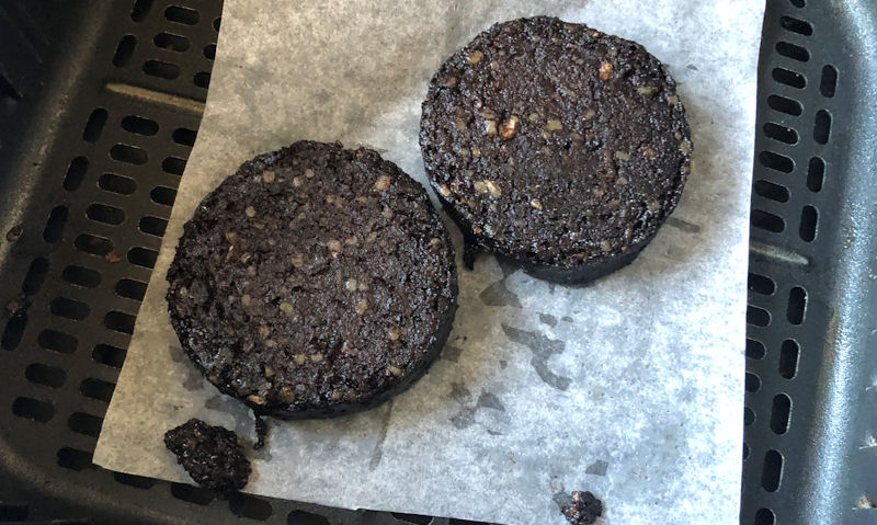 My crumbly cooked black pudding slices sitting on parchment paper in air fryer