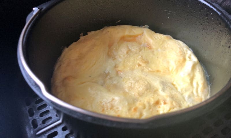 Puffed up omelette inside cake pan placed inside air fryer basket